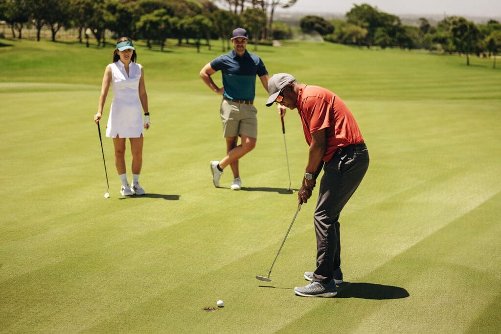 Three people playing golf.