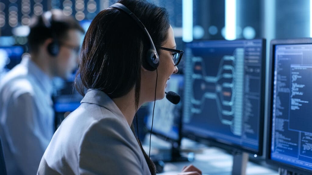A woman with a headset sitting at a computer.
