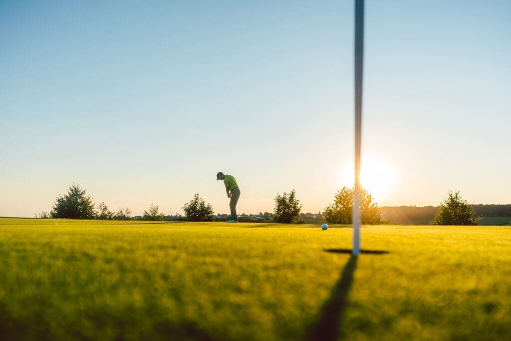 A golfer hits a ball into the hole in the foreground.