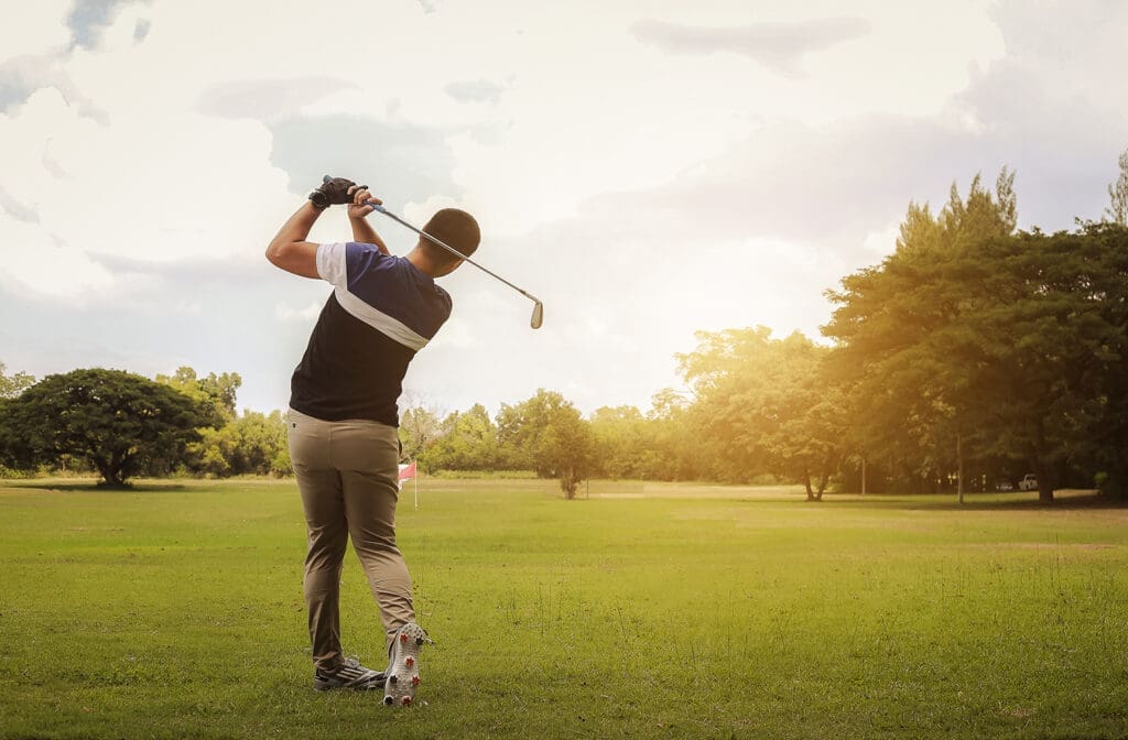 A golfer mid-swing, looking out at their shot.