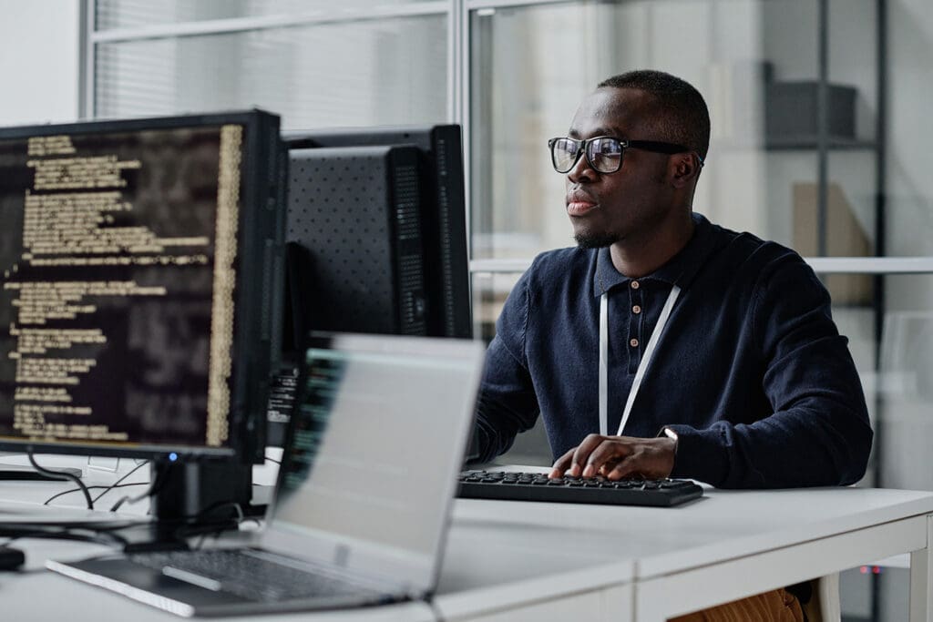 A man wearing glasses sits at his computer, looking somber.